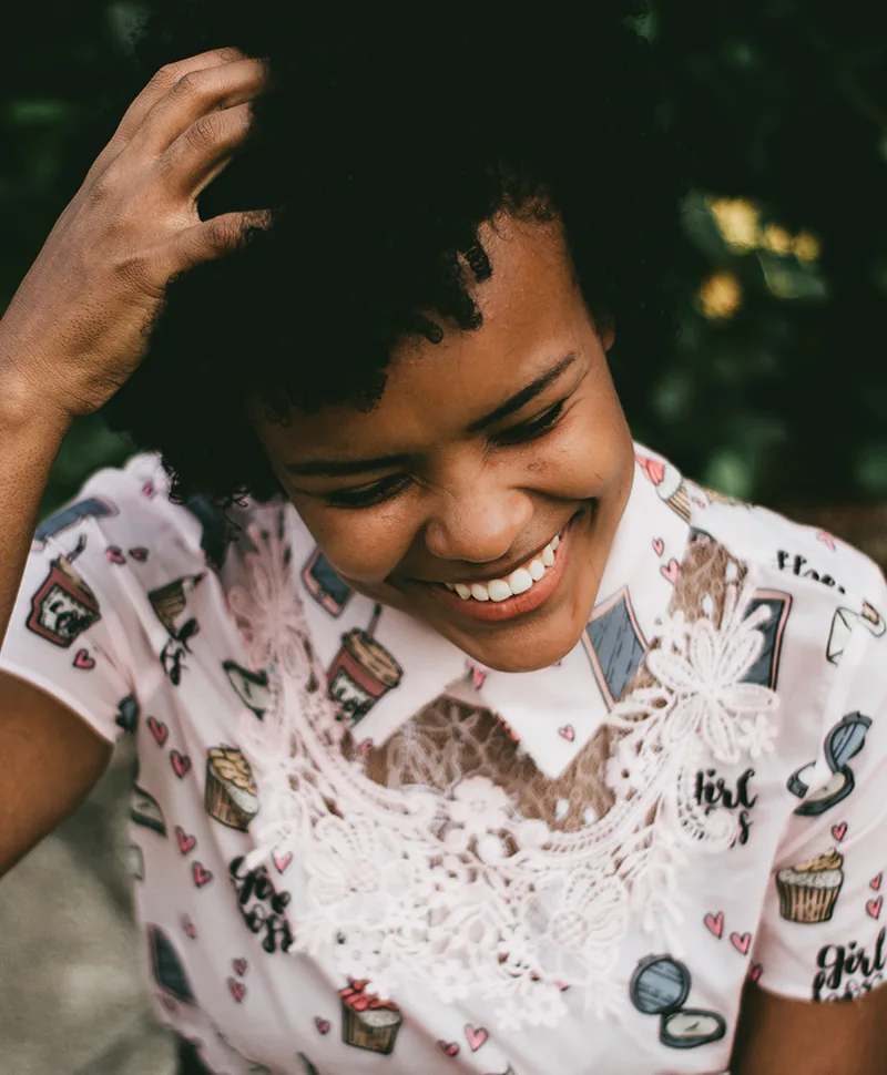 Young black woman smiling and scratching her head.